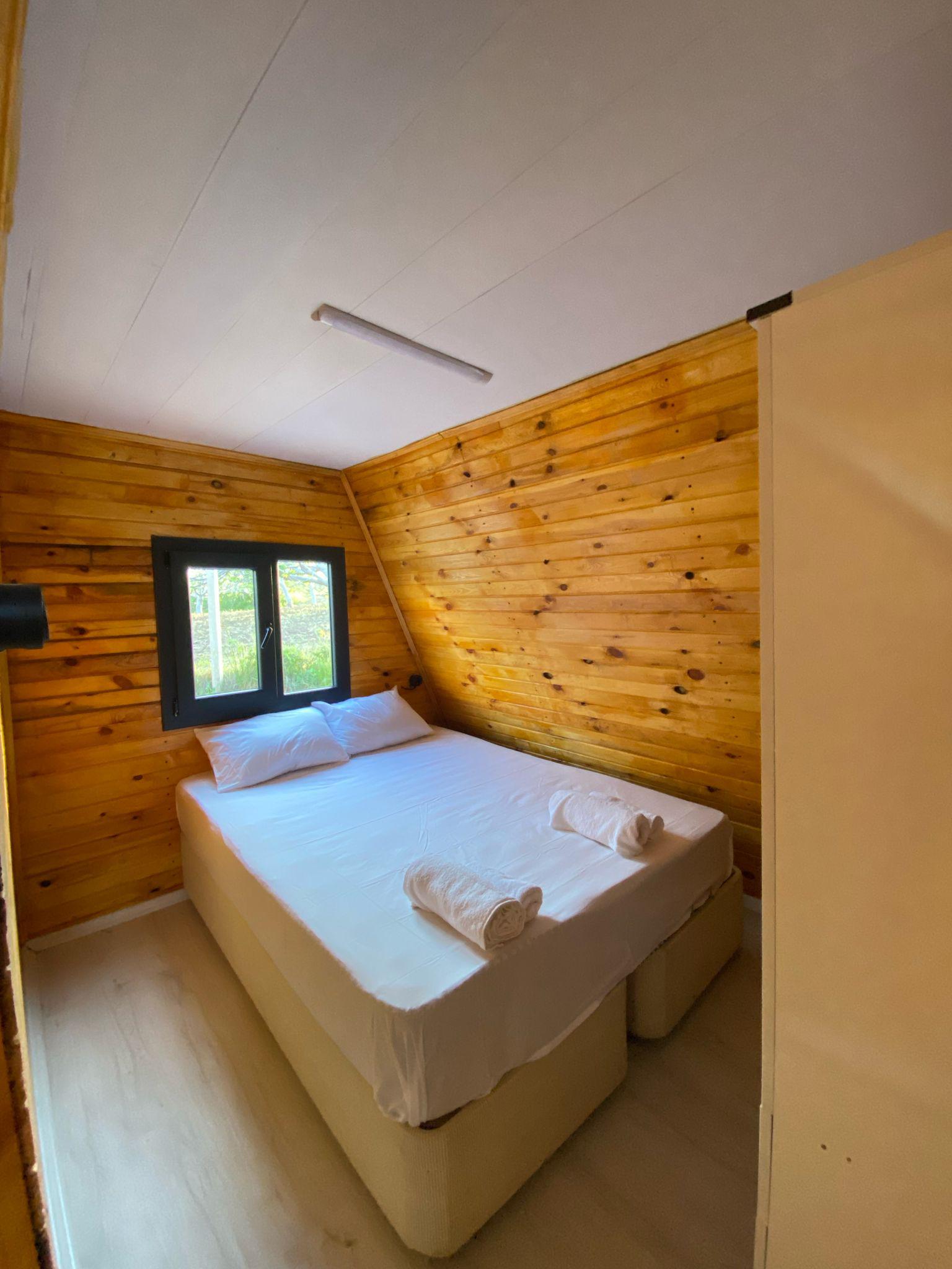 Modern tasarıma sahip bungalov dış cephesi, soft yeşil ve bej tonlarında, geniş cam pencereler ve doğal çevre